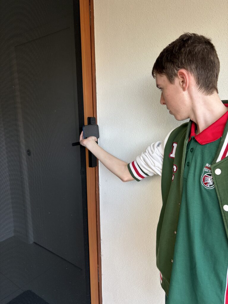 Teenager unlocking a security screen door with an RFID tag attached to a phone